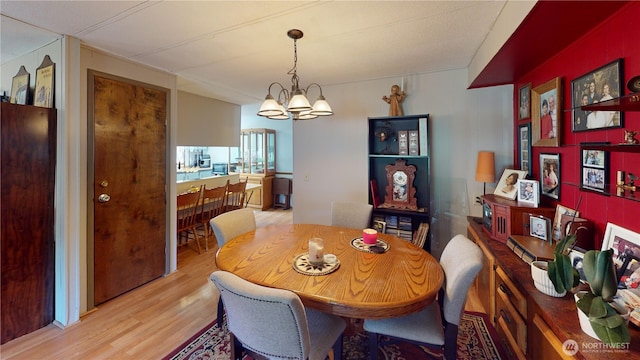 dining space with light wood-style floors and a notable chandelier