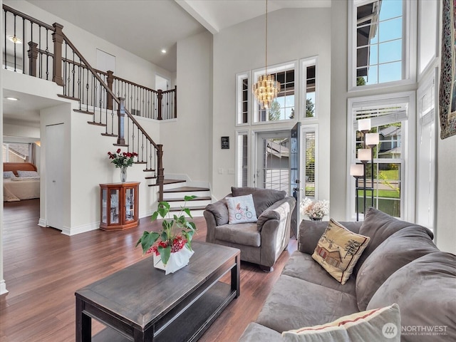 living room featuring stairs, plenty of natural light, wood finished floors, and a towering ceiling