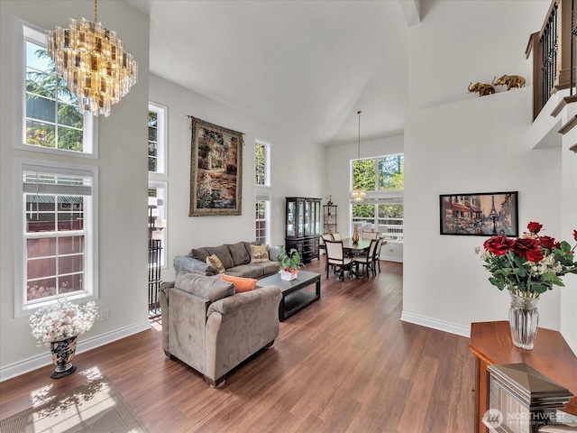living room featuring baseboards, a high ceiling, a chandelier, and dark wood finished floors