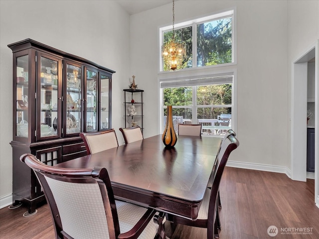 dining room with dark wood-style flooring, baseboards, an inviting chandelier, and a wealth of natural light