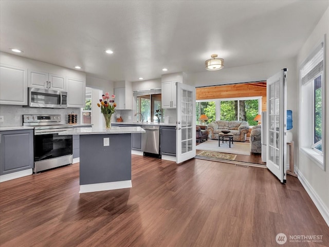 kitchen with light countertops, appliances with stainless steel finishes, plenty of natural light, and a center island