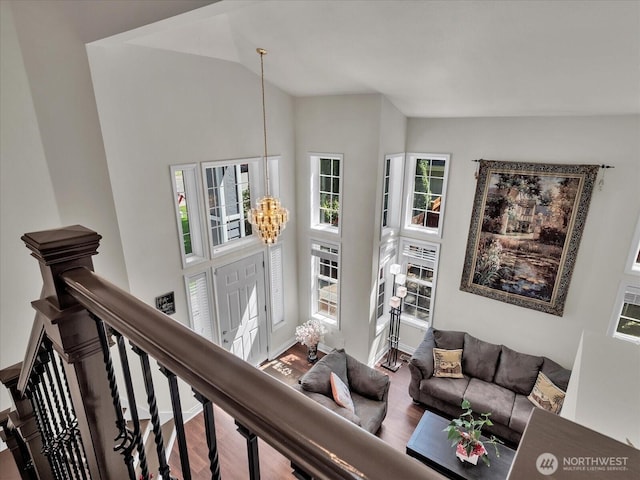 living area with baseboards, high vaulted ceiling, a notable chandelier, and wood finished floors