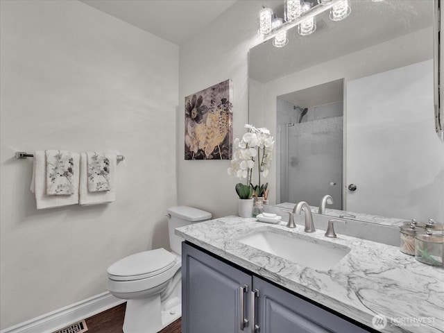 bathroom featuring a shower with shower door, vanity, toilet, baseboards, and wood finished floors