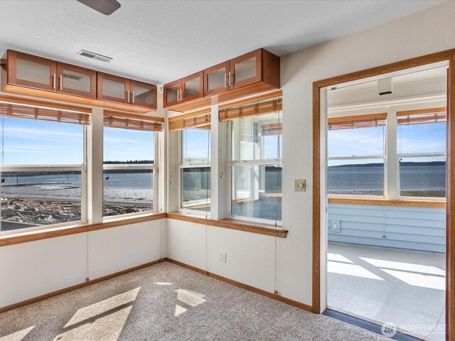 unfurnished sunroom with visible vents and a water view
