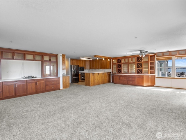 unfurnished living room with light colored carpet and a ceiling fan