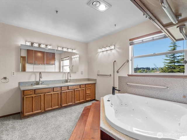 bathroom with a jetted tub, a healthy amount of sunlight, and a sink