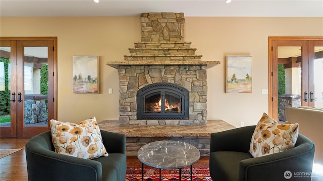 living room with a fireplace, a wealth of natural light, french doors, and wood finished floors