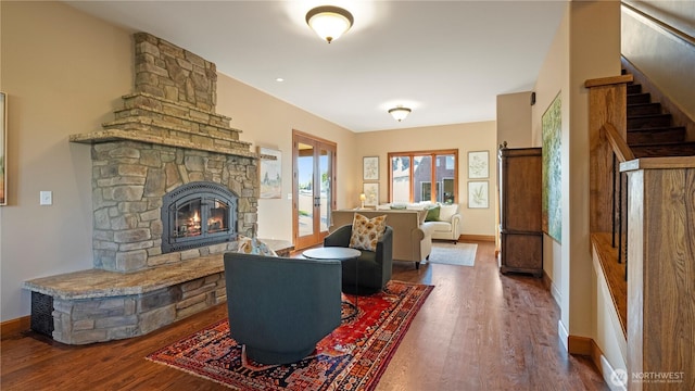 living room featuring stairs, baseboards, wood finished floors, and a fireplace