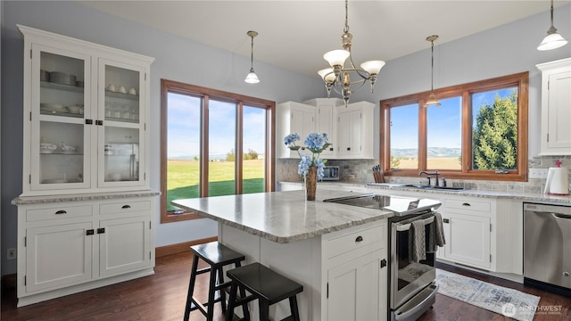 kitchen featuring a sink, stainless steel appliances, white cabinetry, tasteful backsplash, and a kitchen island