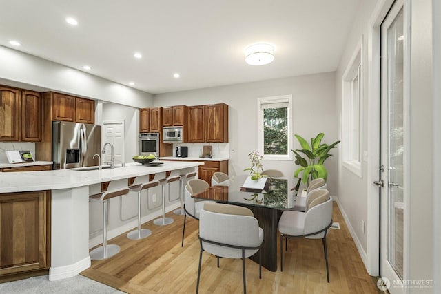 4952 160th Ct SE, Bellevue, WA 98006 - kitchen with a sink, a breakfast bar area, appliances with stainless steel finishes, and light wood-style flooring