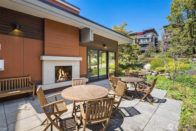 view of patio / terrace featuring a lit fireplace and outdoor dining area