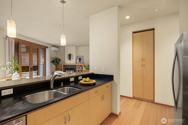 kitchen featuring dark countertops, a wall mounted air conditioner, a sink, light wood-style flooring, and appliances with stainless steel finishes