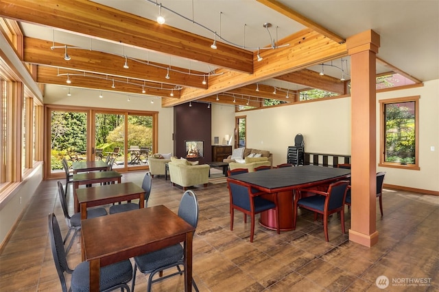 dining space with baseboards, beamed ceiling, and rail lighting