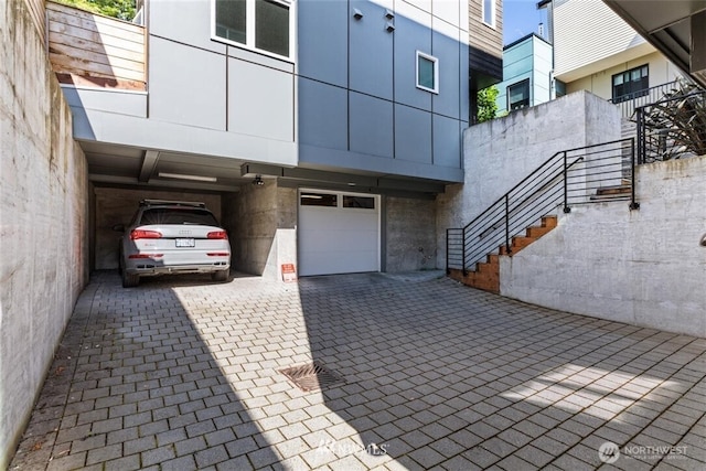 exterior space with an attached garage, decorative driveway, stairway, and a carport