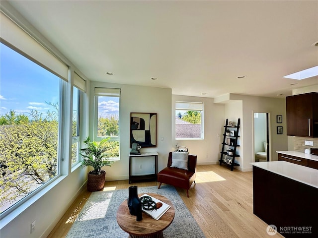 living area with light wood-style floors, plenty of natural light, and a skylight