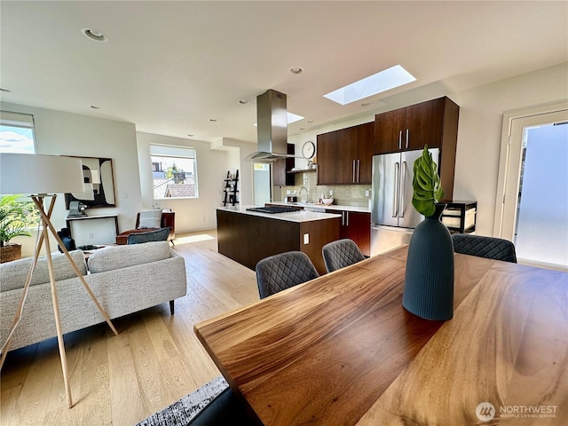 dining room with a skylight, recessed lighting, and light wood-style flooring