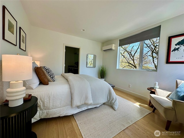 bedroom with wood finished floors, baseboards, and a wall mounted AC