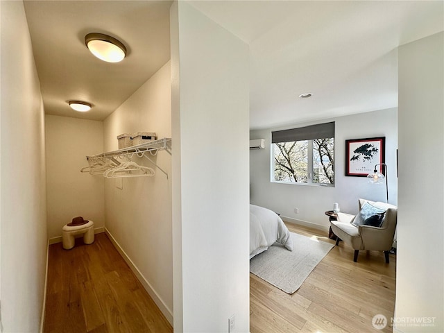 hallway featuring baseboards, a wall mounted AC, and wood finished floors