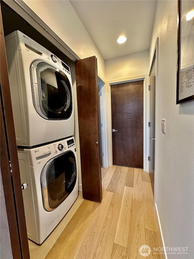 laundry room with laundry area, light wood-style floors, and stacked washer / drying machine