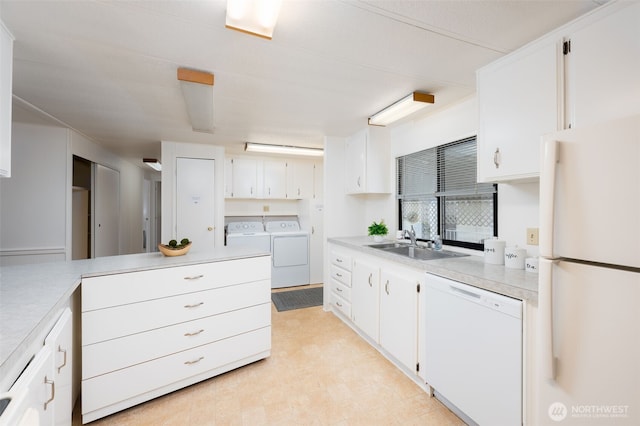 kitchen featuring light countertops, separate washer and dryer, a sink, and white appliances