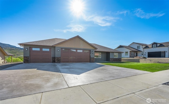 view of front of home featuring concrete driveway, stone siding, a front yard, and a garage