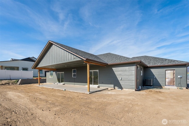 rear view of house featuring a patio, board and batten siding, central AC, and roof with shingles