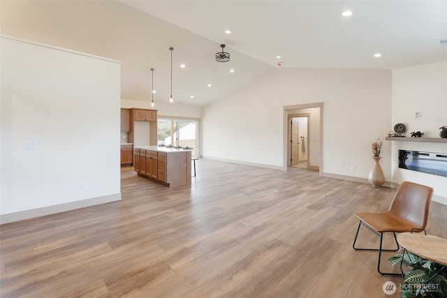 unfurnished living room featuring recessed lighting, a glass covered fireplace, lofted ceiling, and light wood-type flooring