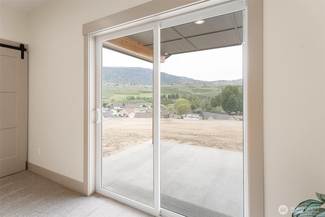 doorway to outside featuring a barn door, a mountain view, and light carpet