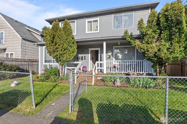traditional-style home with a porch, a front yard, and a fenced front yard