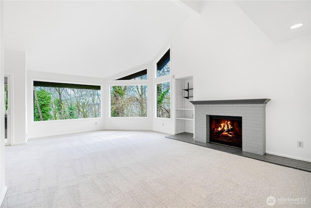 unfurnished living room featuring high vaulted ceiling, carpet floors, a brick fireplace, and baseboards