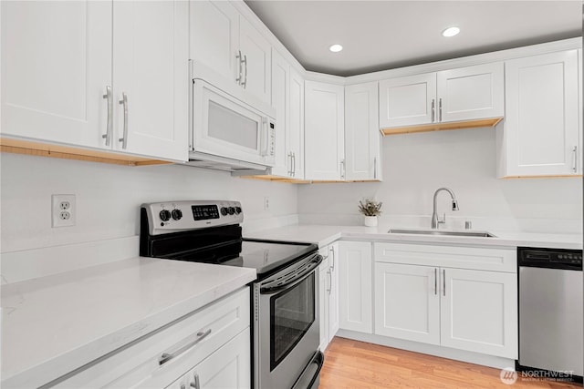 kitchen featuring white cabinets, recessed lighting, stainless steel appliances, a sink, and light wood-style flooring