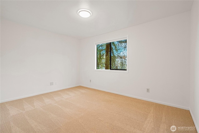 empty room featuring light carpet and baseboards
