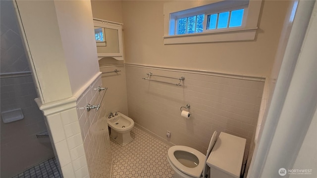 bathroom with tile walls, wainscoting, a bidet, and toilet