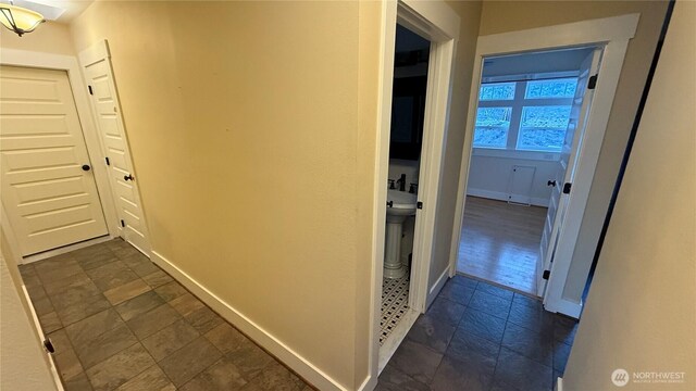 corridor featuring baseboards and stone finish floor