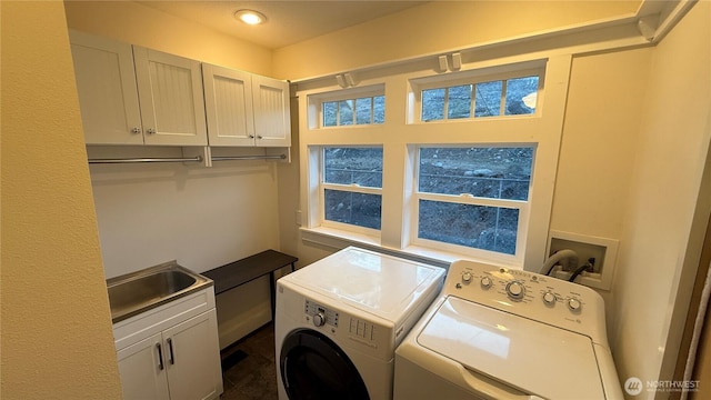 washroom featuring washing machine and clothes dryer, a sink, and cabinet space