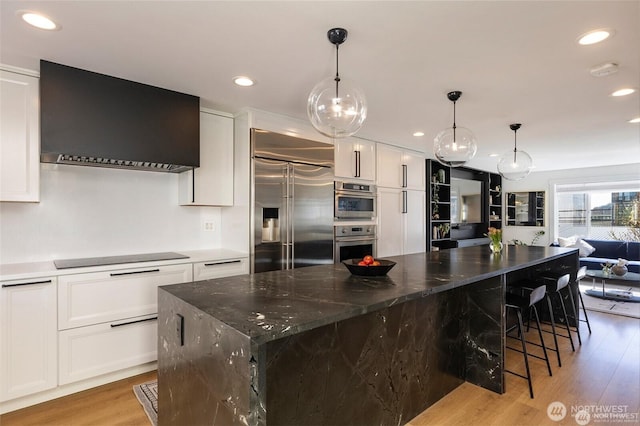 kitchen with stainless steel appliances, wall chimney exhaust hood, light wood finished floors, white cabinets, and recessed lighting