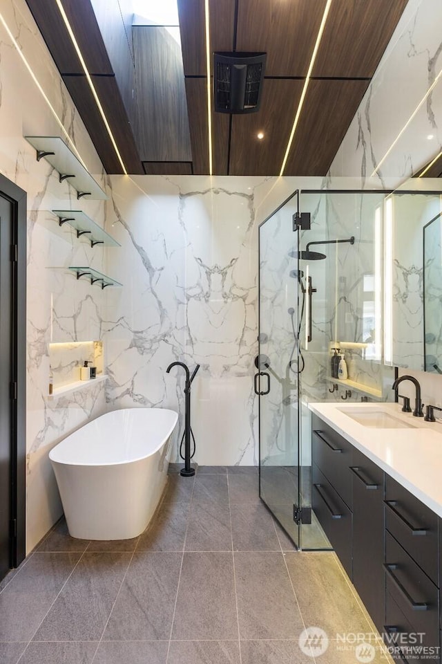 full bath featuring a marble finish shower, vanity, and a freestanding tub