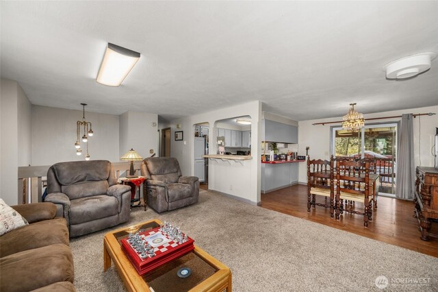 living room featuring carpet, wood finished floors, arched walkways, and a chandelier
