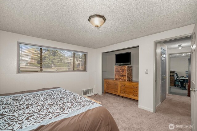 bedroom featuring visible vents, a textured ceiling, and light colored carpet