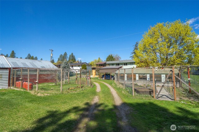view of yard featuring an outdoor structure, a garden, fence, and a greenhouse