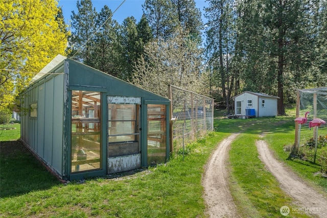 view of greenhouse with dirt driveway and a lawn