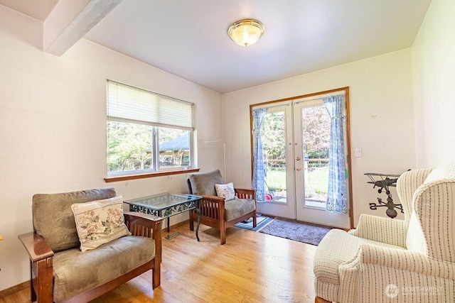 sitting room with light wood-type flooring, a wealth of natural light, and french doors