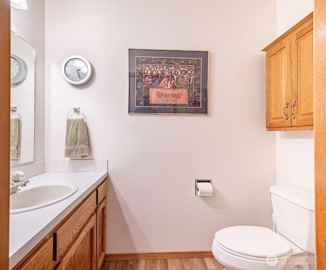 bathroom with wood finished floors, baseboards, vanity, and toilet
