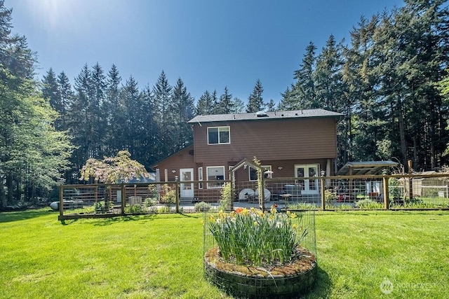 back of house with fence, a garden, and a yard