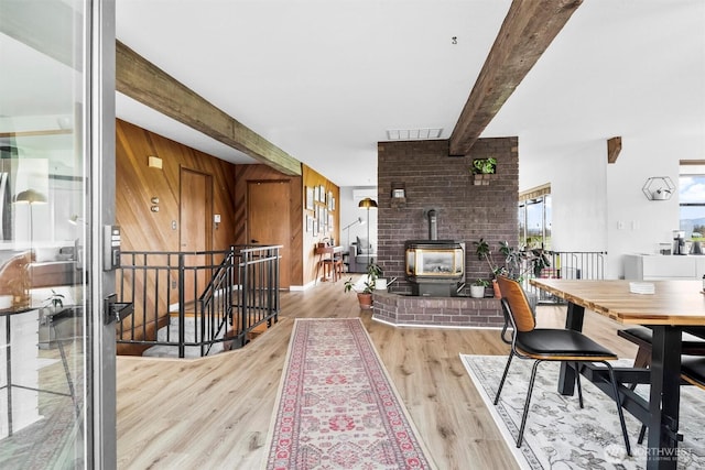 5752 Ronnie Hill Ln, Ferndale, WA 98248 - dining area featuring wood walls, wood finished floors, a wood stove, visible vents, and beam ceiling