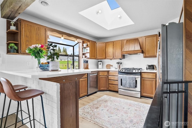 5752 Ronnie Hill Ln, Ferndale, WA 98248 - kitchen featuring a peninsula, a skylight, custom range hood, open shelves, and appliances with stainless steel finishes