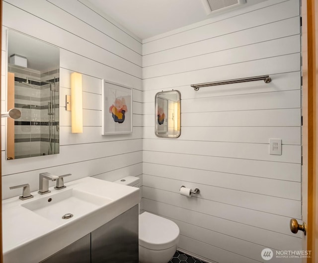 full bathroom with toilet, wood walls, vanity, visible vents, and a shower stall