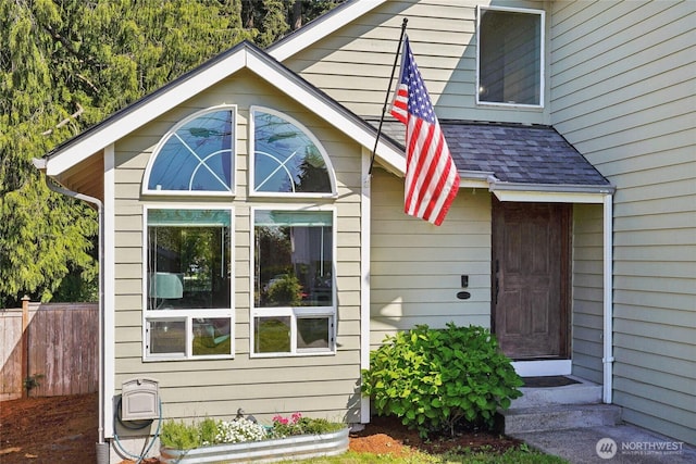 view of home's exterior with fence and roof with shingles