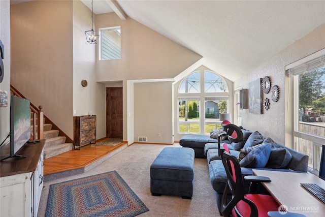 living room featuring high vaulted ceiling, carpet, baseboards, visible vents, and stairway