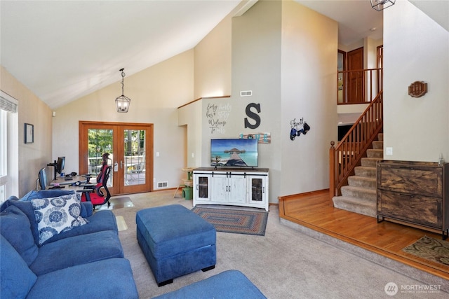 carpeted living room featuring french doors, stairs, visible vents, and high vaulted ceiling